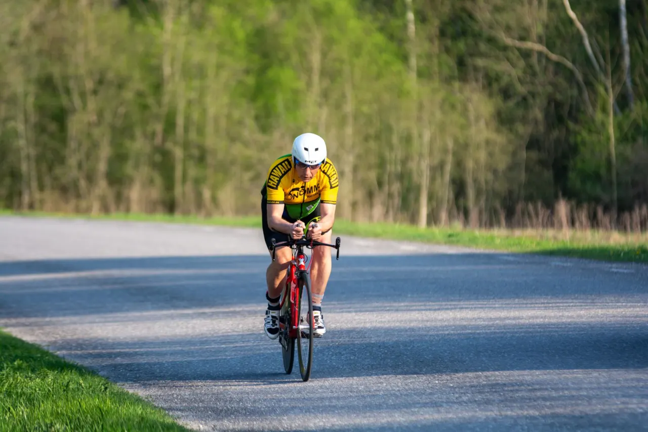 A triathlete riding in an aero position on an open road.